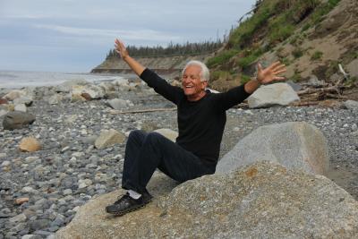 Healthy aging older man smiling with hands wide on the beach