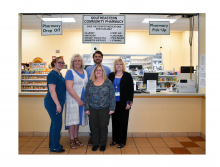 The Southeastern Community Pharmacy team in Gainesville posing for a photo in front of the pharmacy for National Pharmacist Day with medication behind them