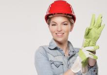 Woman with a hard hat on and cleaning gloves getting ready to work